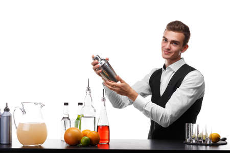 An attractive bartender with a shaker at a bar counter, lime, oranges, lemons isolated on a white background.の写真素材