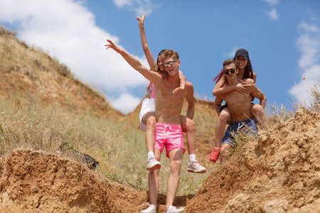 Full-length portrait of boys hold attractive girls in a field on a natural blurred background.の写真素材