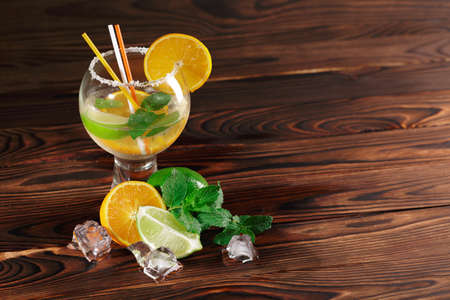 Organic, fresh, healthy, fruity drink in a glass and citrus fruits. Party cocktail on a wooden background. Copy space.の写真素材