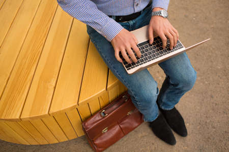 Close-up of typing man. Office worker sitting with a new laptop on the urban background. Progressive technology concept.の写真素材