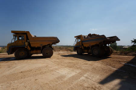 Dump trucks, dumper or tipper trucks in a sand quarry, transporting loose materials on a natural...