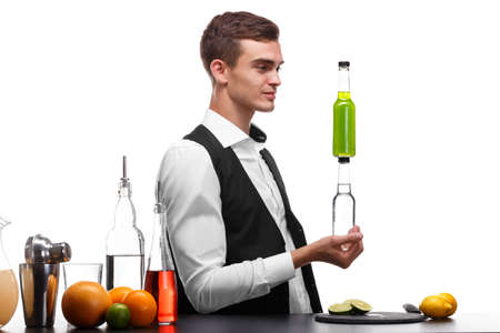 A beautiful bartender holds bottles with beverages, a bar counter with lime, lemon isolated on a white background.の写真素材
