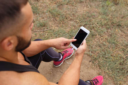 Close-up bodybuilder calling a phone. Muscular man using technology on a blurred background. Active lifestyle concept.の写真素材