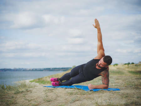 Sporty young man doing yoga practice - concept of healthy life and natural balance between body and mental developmentの写真素材