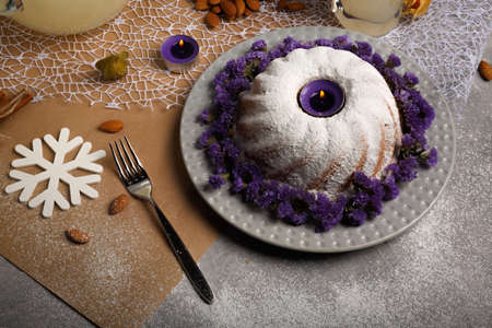 A ring cake sprinkled with sugar powder, almond, cinnamon, physalis on a light colorful background.の写真素材