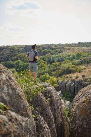 Young man with backpack looking into the distance on the top of mountains. A tourist on a natural...