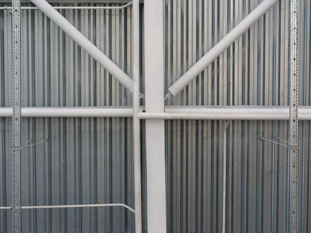 A close-up of a ceiling in a huge warehouse. Inside bright view of iron structure construction as a...