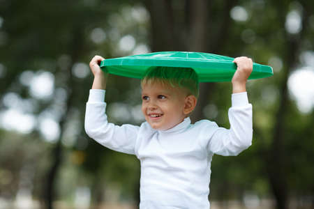 Boy have fun inside recyling waste bin outside. Concept of environmental protection. Colorful boxes.の写真素材