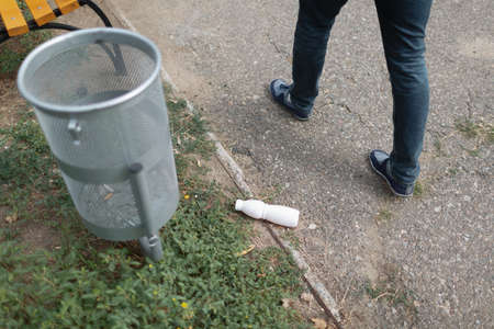 An empty of plastic drinking bottle littering on the road floor, near the rubbish bin. Concept of environmental protection.の写真素材