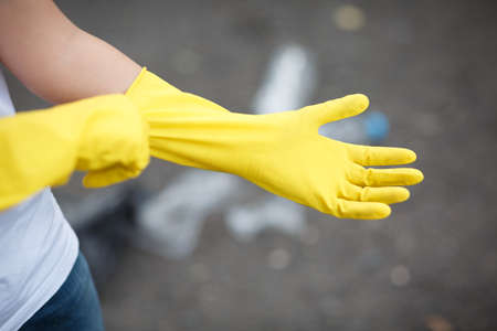 Wearing latex glove for cleaning on hand isolated on asphalt background. Rubbish on the back side.の写真素材