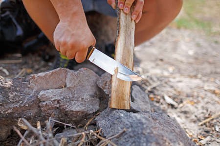 Male camper kindling to start a campfire, bonfire close-up. Man kindles a fire. Fire in nature....