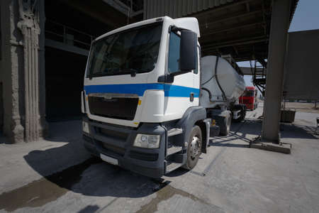 White truck driving along the asphalt road around the factory. Big metal fuel tankers shipping fuel. The truck left the parking lot at the factory. Truck way.の写真素材