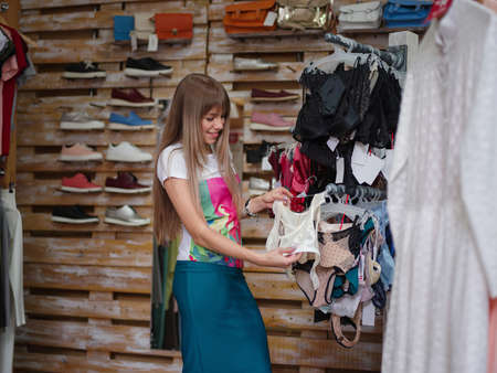 A smiling woman choosing herself sexy underwear in a clothing shop. A female with clothe on a blurred background.の写真素材