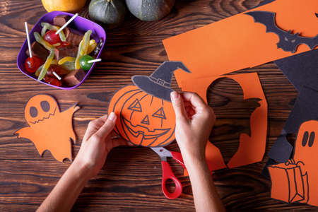 Cloud frame with ghost, pumpkins, spiders and bats cut out of paper. Background of brown wooden boards.の写真素材