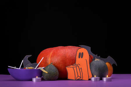 Burning candles. Cloud frame with ghost, pumpkins, spiders and bats cut out of paper. Isolated black background.の写真素材