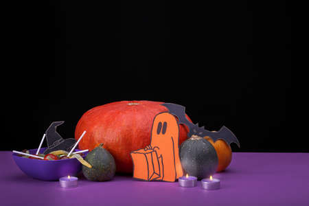 Burning candles. Cloud frame with ghost, pumpkins, spiders and bats cut out of paper. Isolated black background.の写真素材