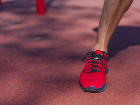 A strong man with sexy body is doing exercises on his feet. A handsome young man lifts weights with his feet in the park.の写真素材