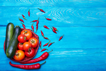 Red tomatoes with chili peppers and green zucchini on a wooden background. Ketchup sauce ingredients. Vegetables.の写真素材