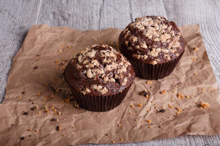Close-up two chocolate muffins with nuts on a table background. Chocolate cupcakes. Homemade pastry.の写真素材