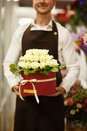 Close-up of florist holding flowers on a blurred background. Man presenting a bouquet. Decor concept.の写真素材
