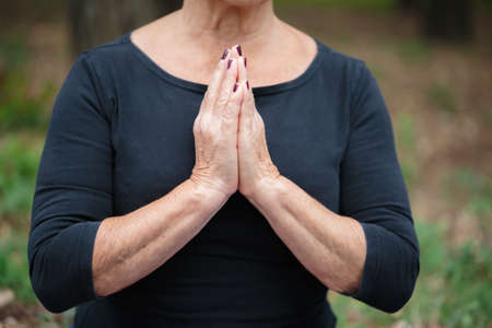 Close-up meditating old woman on a garden background. Zen and meditation concept.の写真素材