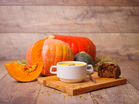 Hot yellow soup with pumpkins and zucchini on a rustic background. Autumn cafe soups. Copy space.の写真素材