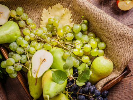 Mix of fruits on a rustic background. Green grape and organic pears on fabric. Close-up ripe fruits.の写真素材