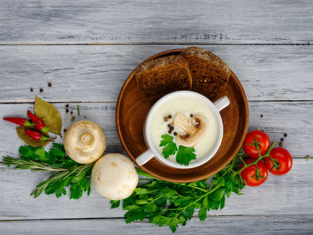 Creamy mushroom soup with black pepper serve with black bread tomatoo garlic pepper on a litter of brown color. Close-up of soup. Copy space. Food concept.の写真素材