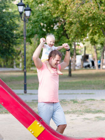 Happy dad and toddler boy having fun on a playground on a blurred background. Single father concept.の写真素材