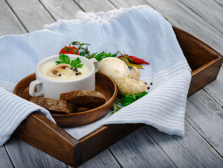 Creamy mushroom soup with black pepper serve with black bread tomatoo garlic pepper on a litter of brown color. Close-up of soup. Copy space. Food concept.の写真素材
