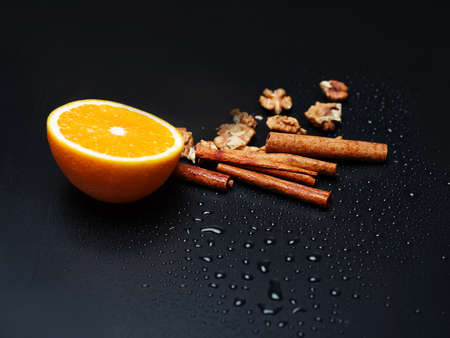 Walnuts, delicious fresh orange and cinnamon sticks are depicted on dark gray background. Copy space. Close-up of objects.の写真素材