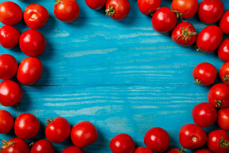 Top view of colorful, fresh tomatoes on a blue wooden background. Italian cafe, restaurant. Copy space.の写真素材