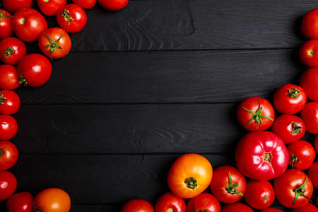 Top view of colorful, fresh tomatoes on a black wooden background. Italian cafe, restaurant. Copy space.の写真素材