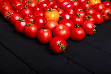 Close-up bright red small cherry tomatoes on a wooden table background. Nutritious tomato vegetables for vegetarians.の写真素材