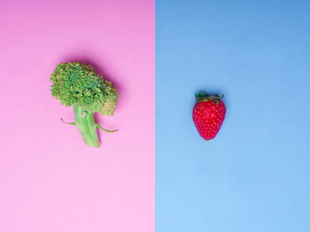 Fesh green broccoli lies on a pink background. Tasty ripe strawberry is depicted on a blue background. Copy space. Close-up of vegetables.の写真素材