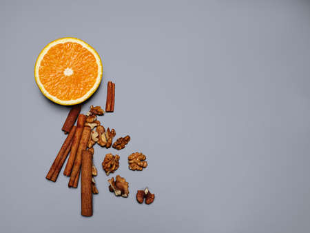 Walnuts, delicious fresh orange and cinnamon sticks are depicted on a gray background. Copy space. Close-up of objects.の写真素材