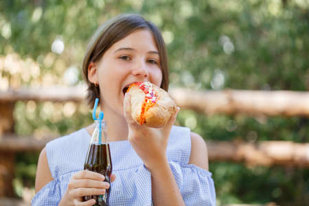 Pretty girl with tasty fast food outdoors. Picnic on the nature.の写真素材