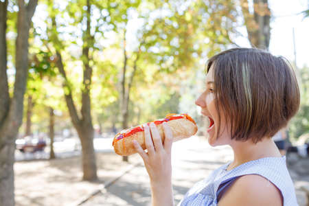 Pretty girl with tasty fast food outdoors. Picnic on the nature.の写真素材