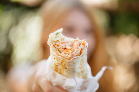 Tasty shawarma with vegetables on the nature. Close-up of fast food outdoors.の写真素材
