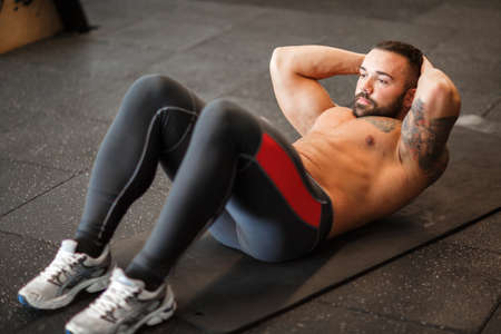 Muscular man working out in gym doing exercises.