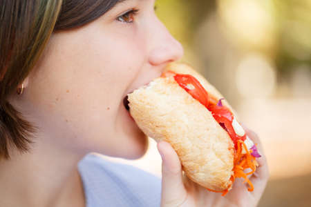 Pretty girl with tasty fast food outdoors. Picnic on the nature.の写真素材