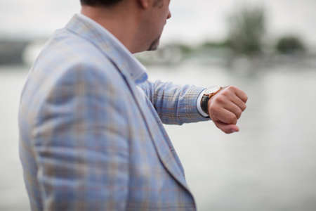 Close-up man with watch on a hand. Businessman checking time on a blurred city background. Business concept. Copy space.の写真素材