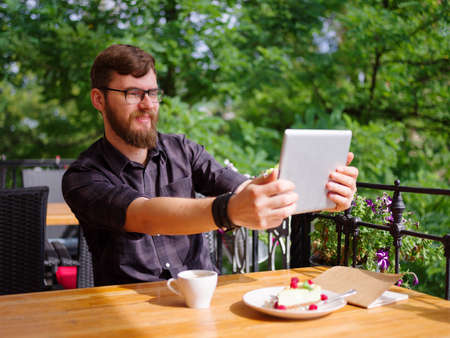 Goodly young man working on tablet while sitting outdoors . Business concept.の写真素材