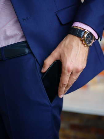 View of male hands touching mobile phone in a blue suit. Business concept.の写真素材