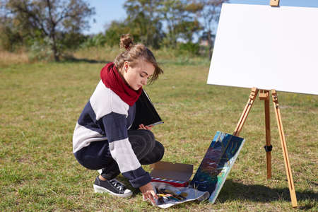 Young artist painting an autumn landscape on the nature background. Art concept.の写真素材