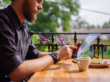 Goodly young man working on tablet while sitting outdoors . Business concept.の写真素材