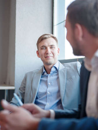 Young attractive business man talking to colleague in the office. Business concept.の写真素材
