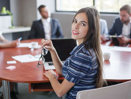 Young beautiful girl working and posing at the camera in the office. Business concept.の写真素材