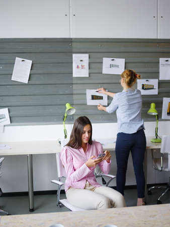 Beautiful young woman working in the office grey wall with scraps on the background. Business concept.の写真素材