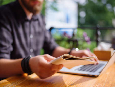 Pretty young man working in the cafe with laptop and copybook. Business concept.の写真素材